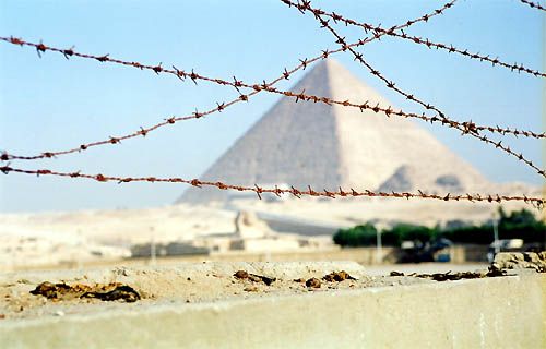 Un mur muni de barbelés est en construction autour des pyramides