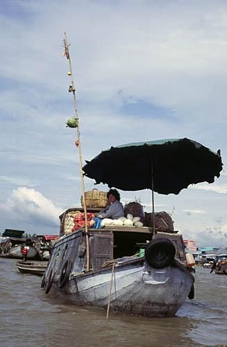 Marché flottant. Ce qu'elle vend est montré par son baton contenant des échantillons.